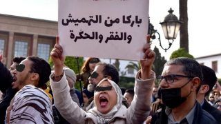 A Moroccan woman raises a placard as she takes part in a protest against rising prices, in front of the parliament in the capital Rabat, on February 20, 2022. (Photo by AFP)